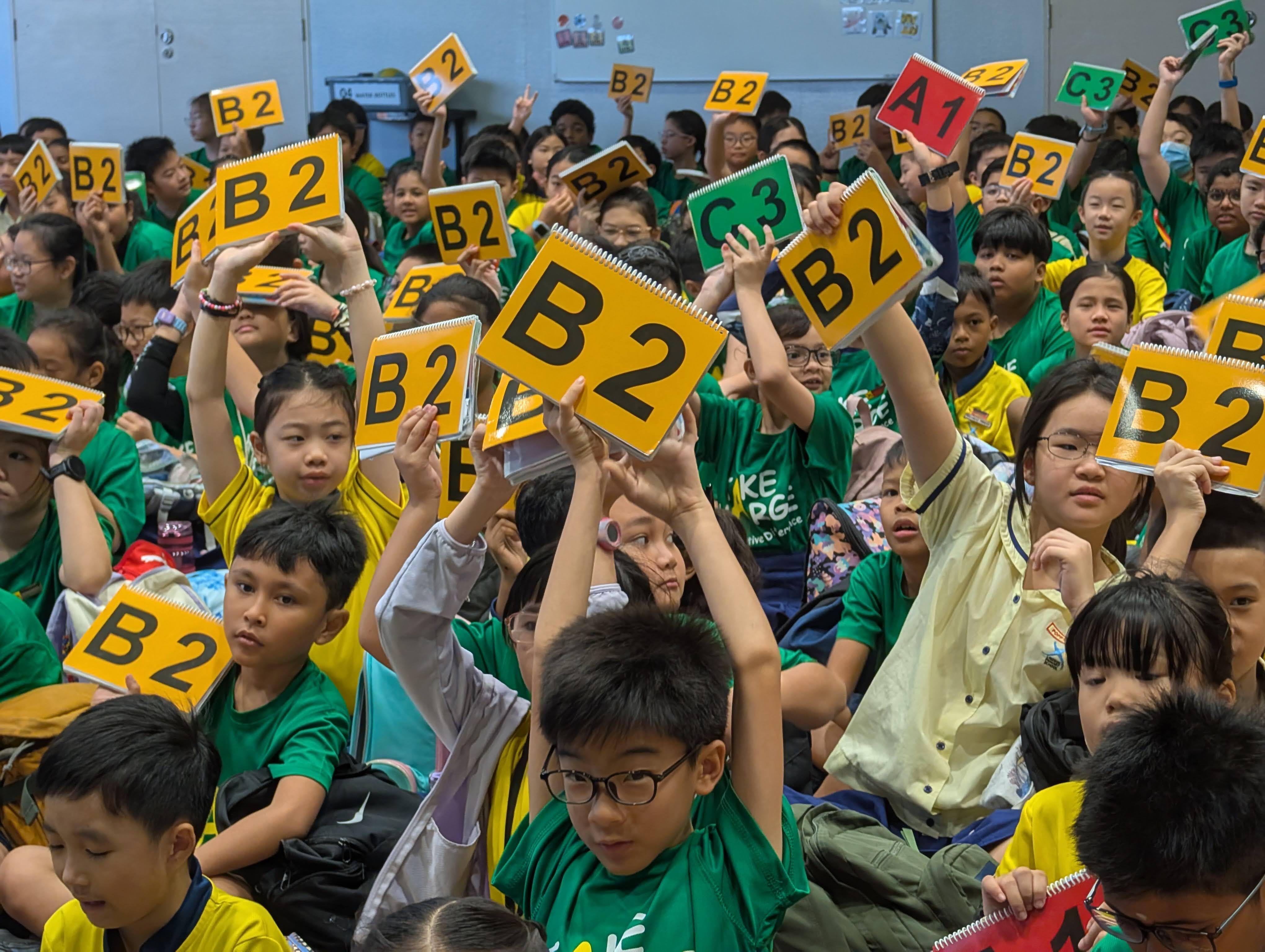 Students in the hall participating in the quiz segment with the alphabet sheets in their handbook